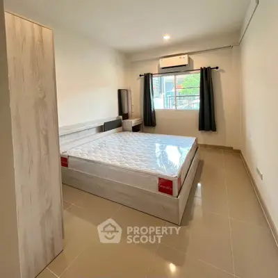 Spacious bedroom with modern design and natural light, featuring a comfortable bed and sleek flooring.
