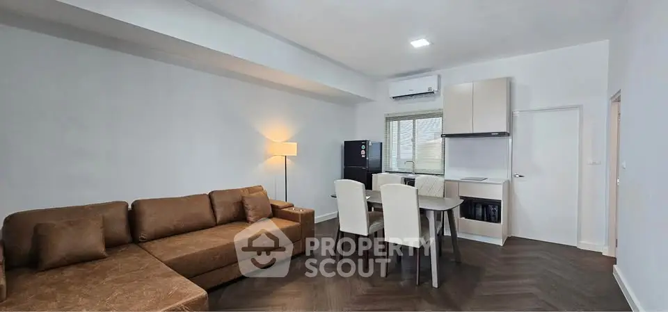 Modern living room with brown sofa and dining area in open layout apartment.