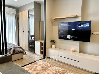 Modern studio apartment with sleek design, featuring a cozy living area and stylish bedroom separated by glass partition.