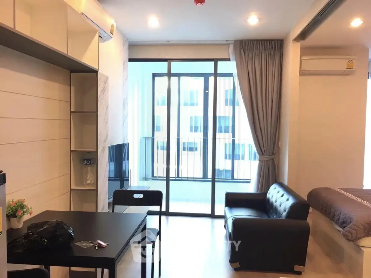 Modern studio apartment with open layout, featuring a cozy living area and large windows for natural light.