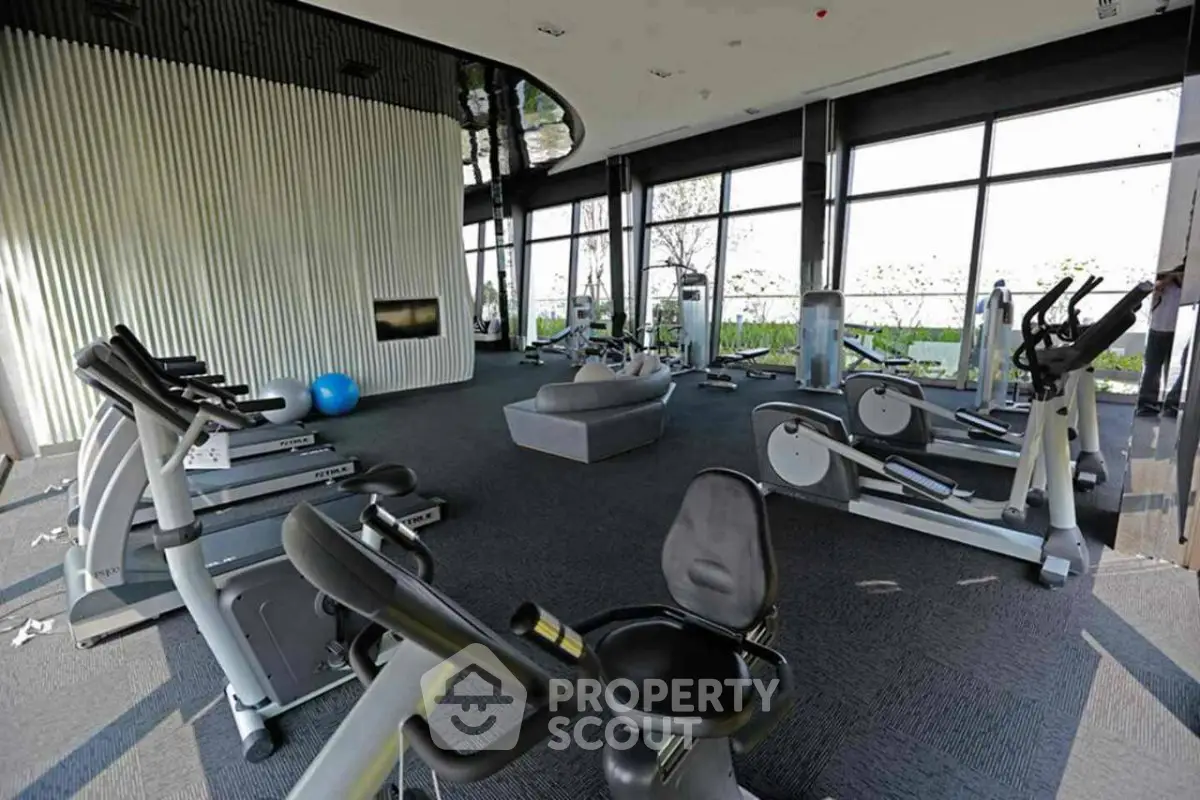 Spacious modern gym with state-of-the-art equipment and panoramic windows offering scenic views.