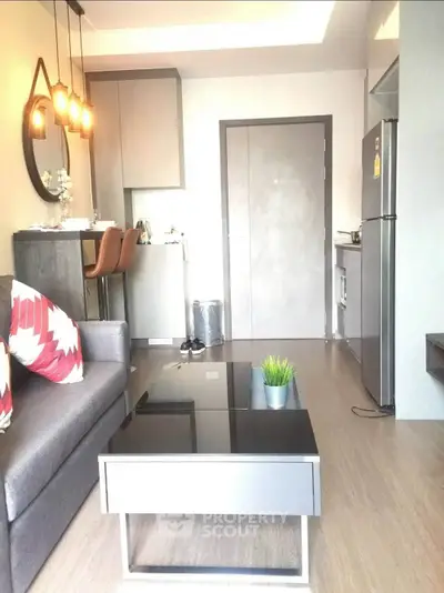 Modern living room with stylish decor and open kitchen layout, featuring sleek furniture and ambient lighting.