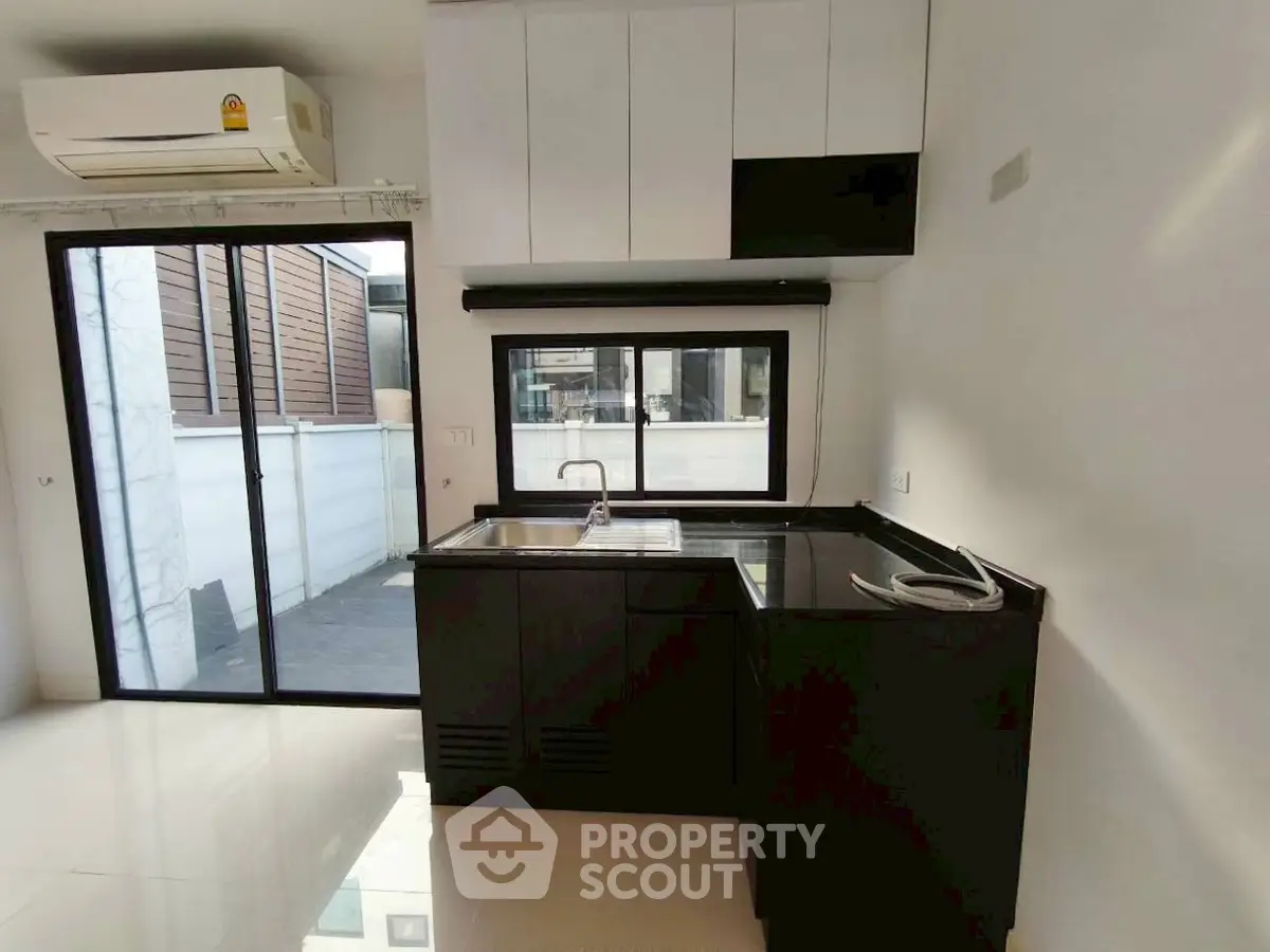 Modern kitchen with sleek black cabinetry and large window for natural light.