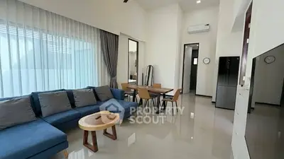 Modern living room with sleek furniture and open layout, featuring a stylish blue sofa and dining area.