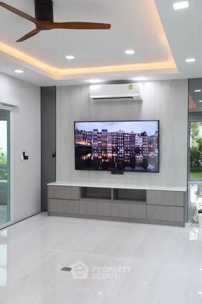 Modern living room with sleek design, featuring a wall-mounted TV and stylish ceiling fan.