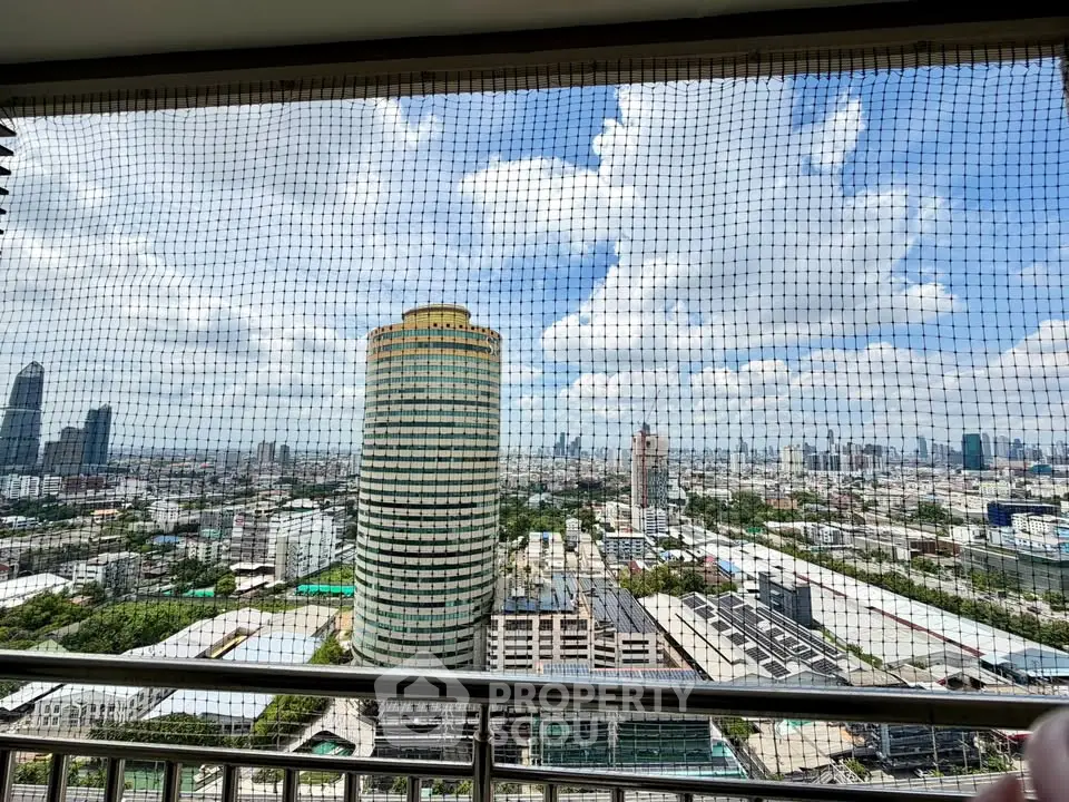 Stunning cityscape view from high-rise balcony with safety netting and clear blue sky.