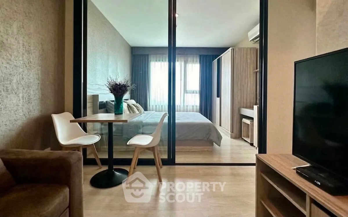 Modern apartment interior with glass partition, cozy bedroom, and stylish dining area.