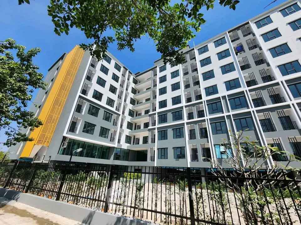 Modern multi-story apartment building with sleek design and lush greenery.