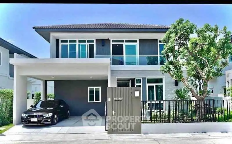 Modern two-story house with sleek design and spacious driveway in a suburban neighborhood.