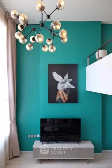 Modern living room with teal accent wall, stylish chandelier, and sleek TV setup.