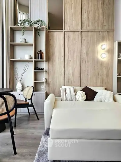 Modern living room with stylish decor and cozy seating area, featuring elegant wooden shelving and contemporary lighting.