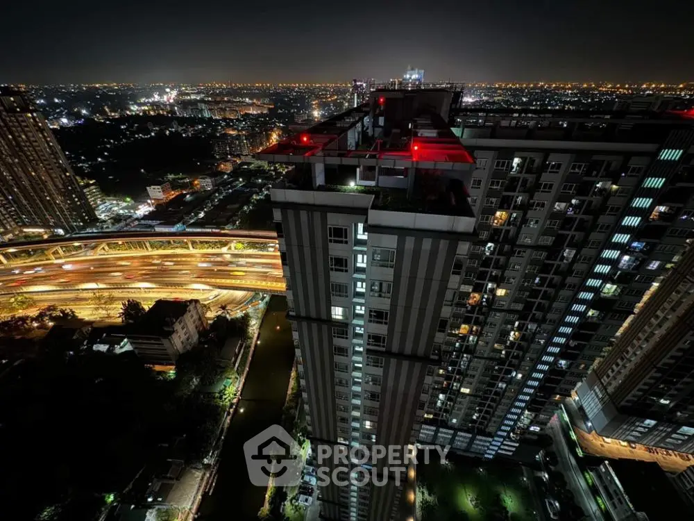 Stunning night view of high-rise building with city lights and highway in the background.