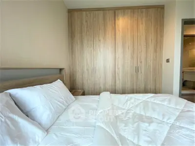 Cozy bedroom with wooden wardrobe and plush bedding in modern apartment.