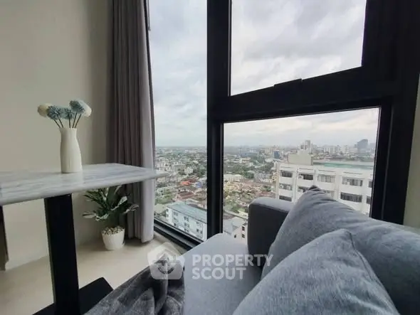 Modern living room with panoramic city view from large windows, featuring stylish decor and cozy seating.