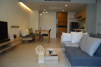 Modern open-plan living room with cozy seating and stylish kitchen area in a contemporary apartment.