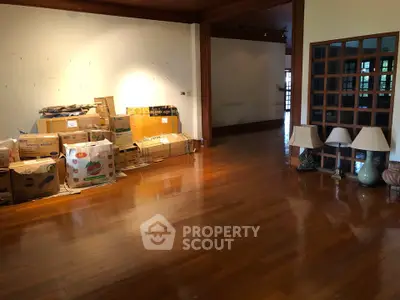 Spacious living room with wooden flooring and moving boxes, ideal for customization.