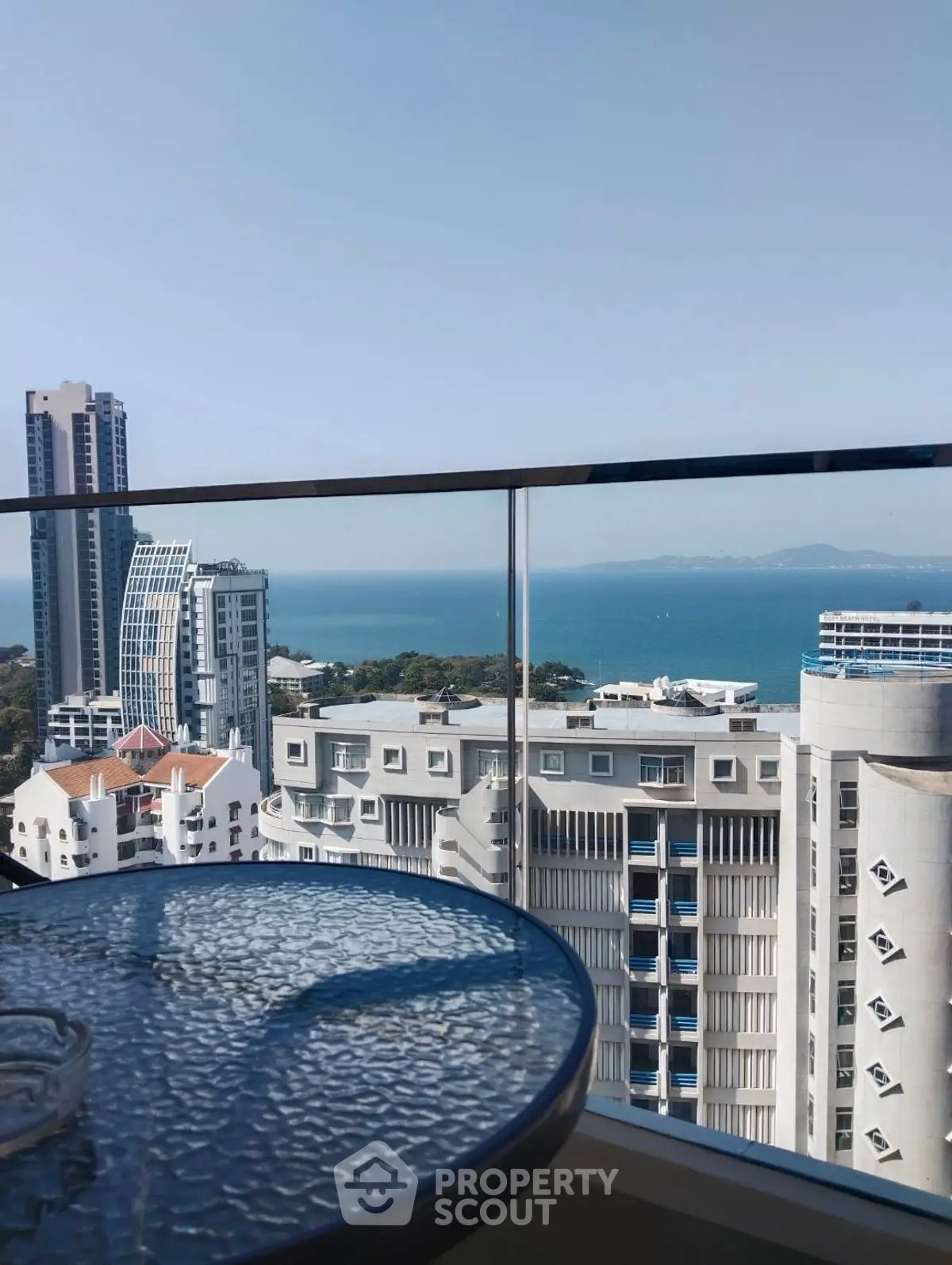 Stunning high-rise balcony view overlooking the ocean and city skyline, perfect for urban living.