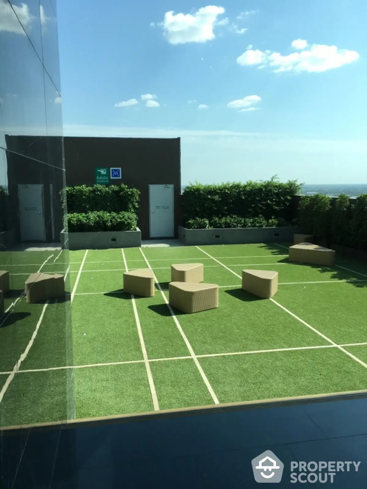 Modern rooftop terrace with stylish seating and lush greenery under a clear blue sky.