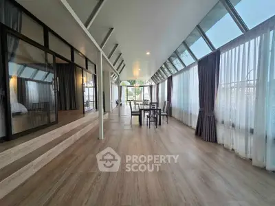 Spacious modern living area with floor-to-ceiling windows and elegant dining setup.