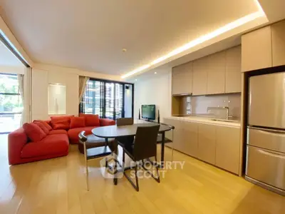 Modern open-plan living room with red sofa and sleek kitchen in luxury apartment.