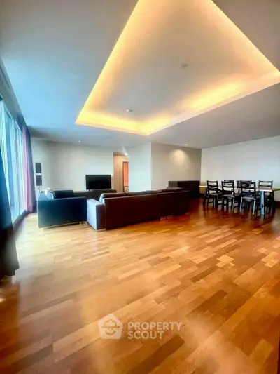 Spacious modern living room with elegant wooden flooring and ambient lighting, perfect for family gatherings.