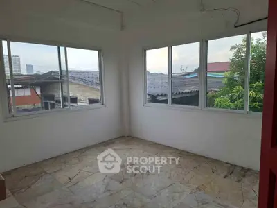Spacious room with large windows offering natural light and urban views, ideal for versatile living space.