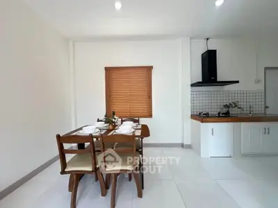 Modern kitchen with dining area featuring wooden table and chairs, sleek cabinetry, and gas stove.
