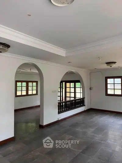 Spacious open-plan living area with elegant archways and large windows for natural light.
