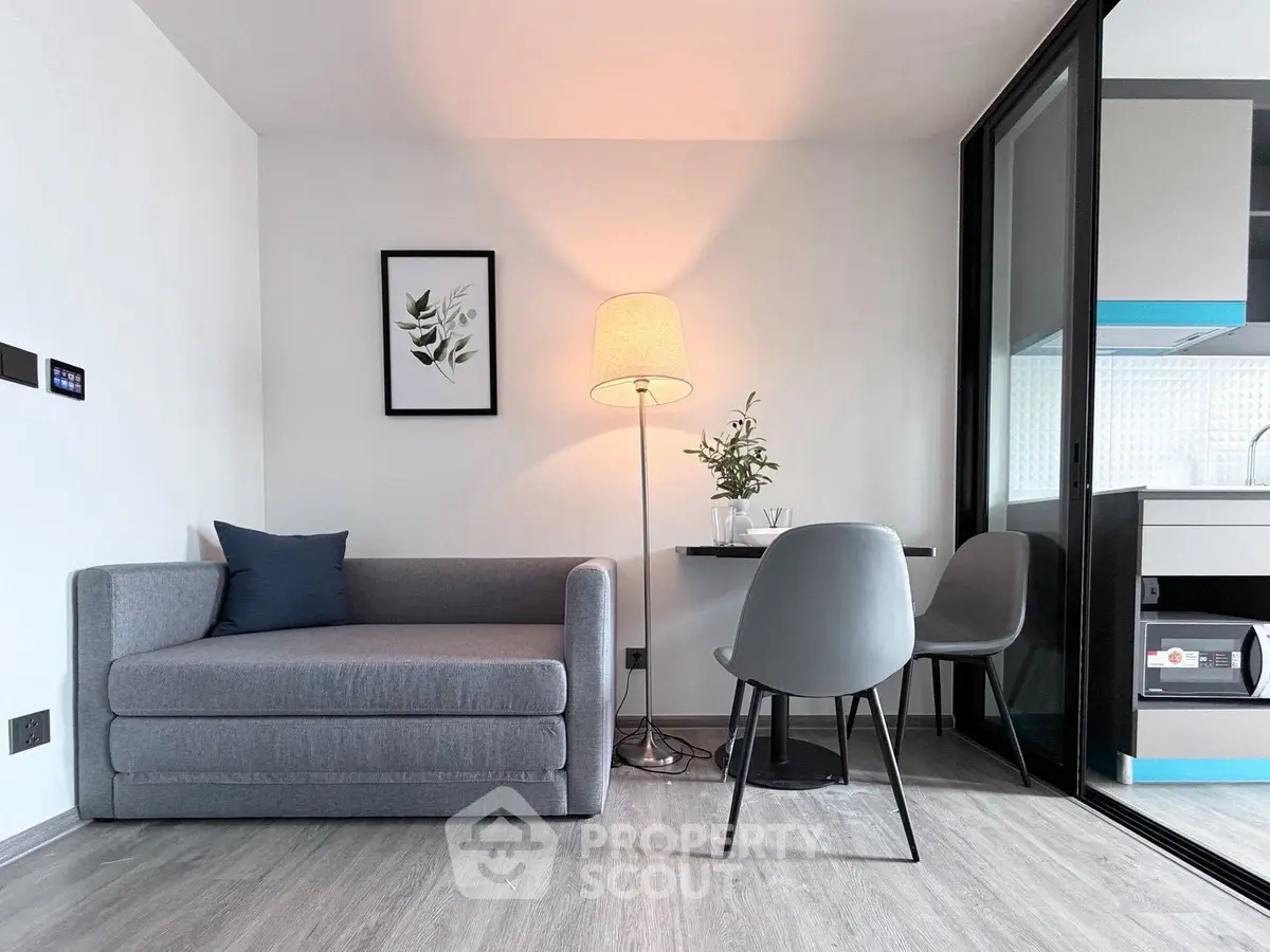 Modern living room with stylish decor and open kitchen layout, featuring a cozy gray sofa and elegant lighting.