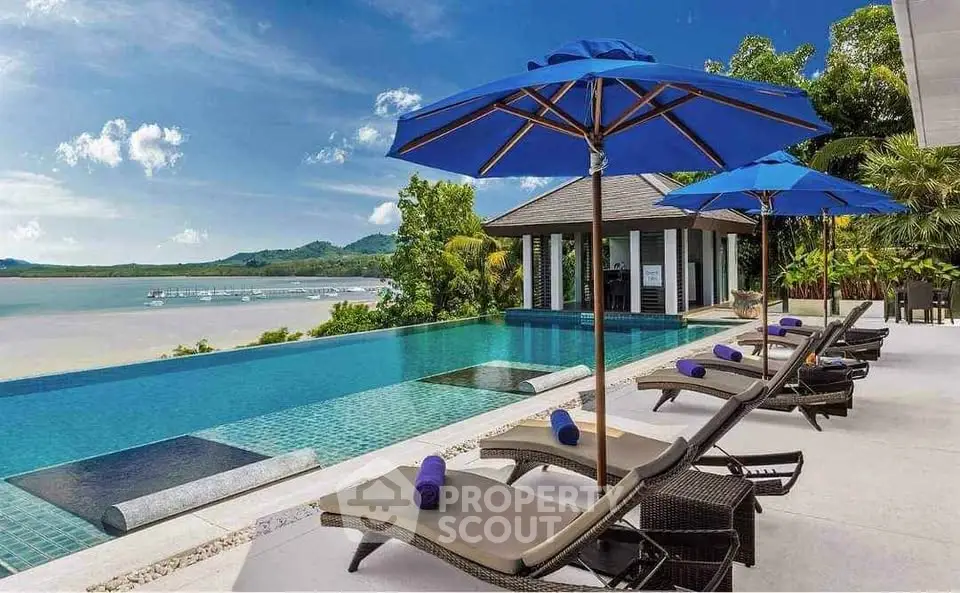 Luxurious infinity pool with stunning ocean view and sun loungers in tropical paradise.