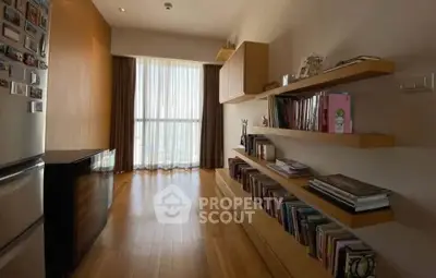 Stylish apartment with wooden flooring and built-in bookshelves, featuring a bright window view.