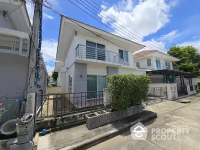 Modern two-story house with balcony and driveway in a suburban neighborhood