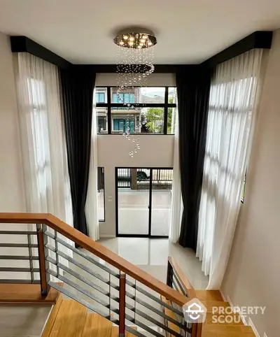 Elegant modern staircase with large windows and chandelier in luxury home