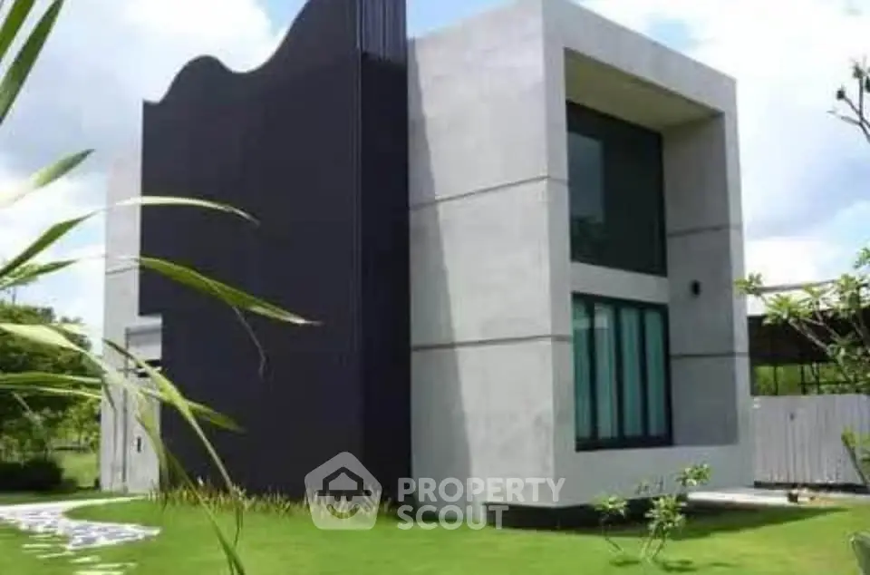 Modern minimalist house with unique architectural design and lush green lawn.