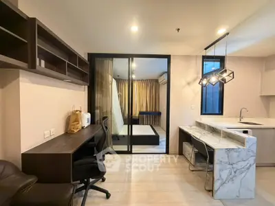 Modern apartment interior with study area and open kitchen design, featuring sleek furniture and ample lighting.