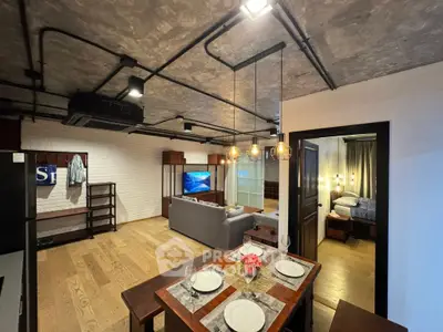 Stylish open-concept living and dining area with modern industrial design and cozy bedroom view.