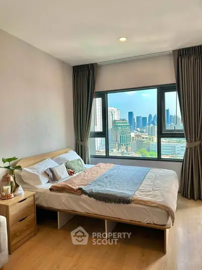 Spacious bedroom with city view, featuring modern decor and large windows for natural light.