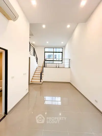 Spacious modern living room with high ceilings and sleek staircase in a contemporary home.