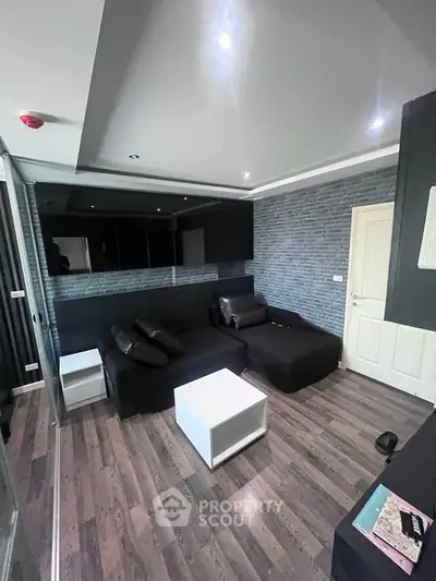 Modern living room with sleek black furniture and stylish wood flooring