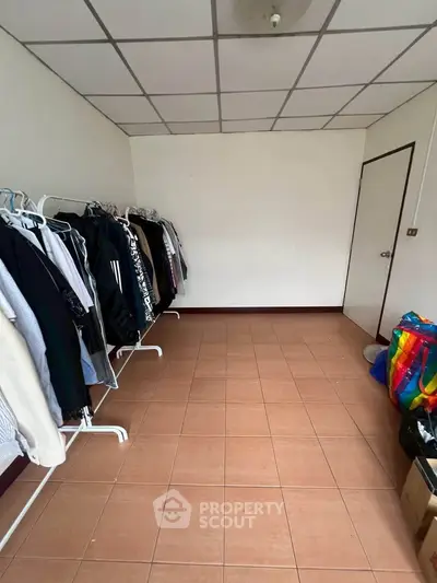Spacious storage room with tiled floor and clothing racks, ideal for organizing belongings.