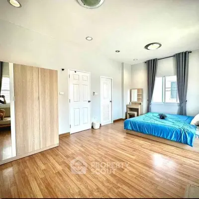 Spacious bedroom with wooden flooring and modern furnishings