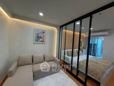 Modern living room with cozy sofa and stylish bedroom separated by glass partition, featuring elegant lighting.