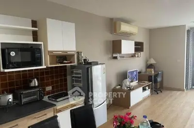 Modern open-layout living room with kitchen, featuring sleek appliances and stylish decor.