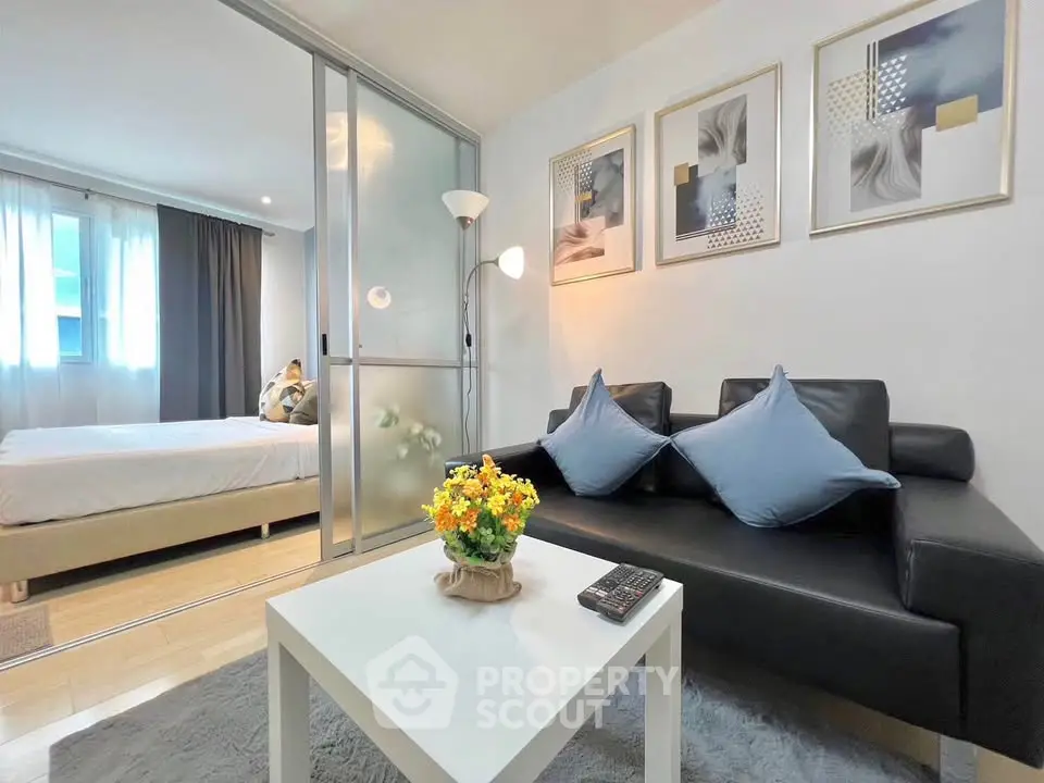 Modern living room with sleek black sofa and cozy bedroom view