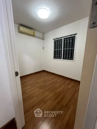 Cozy small room with wooden flooring and air conditioning, perfect for a compact living space.