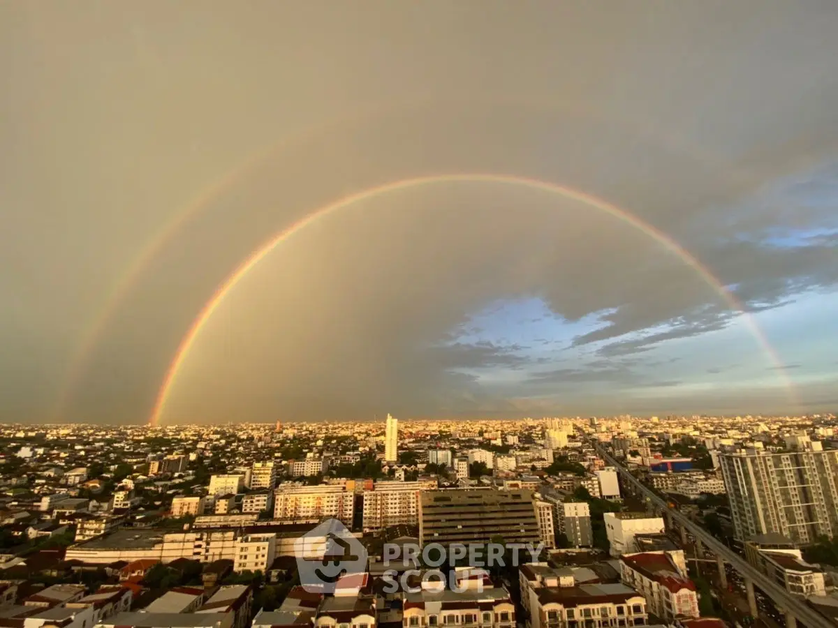 Stunning cityscape view with a vibrant double rainbow arching over urban skyline.