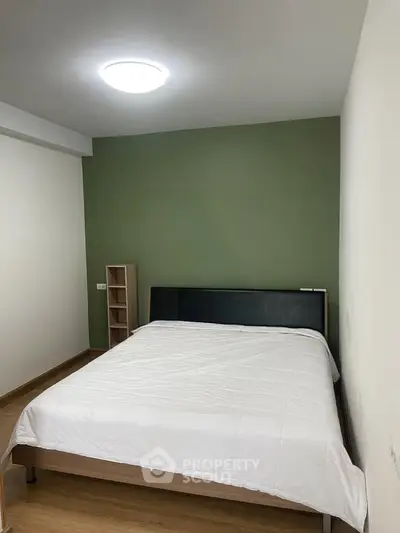 Cozy bedroom with modern design and green accent wall, perfect for relaxation.