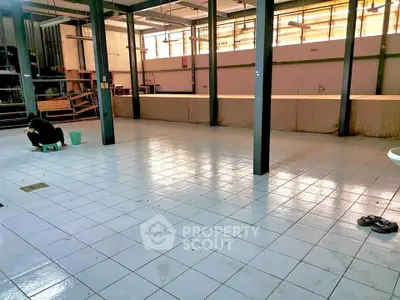 Spacious industrial-style open area with tiled flooring and metal beams, ideal for creative workspace or storage.