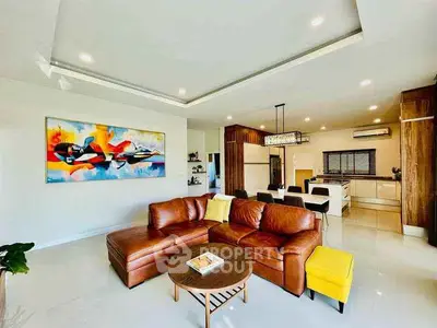 Spacious modern living room with leather sofa and open kitchen layout
