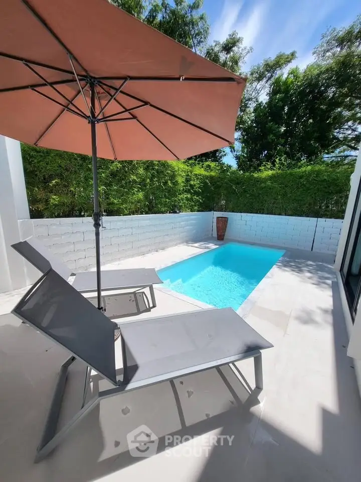 Luxurious private pool area with modern sun loungers and umbrella, perfect for relaxation and leisure.